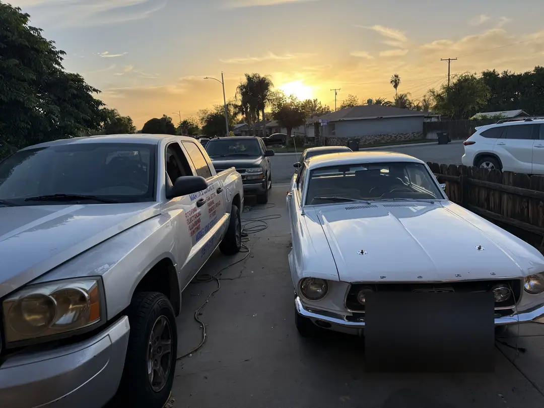 1967 Mustang next to a pickup in the Supercanic driveway at sunset