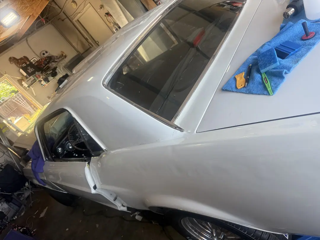 1967 Mustang being vinyl wrapped Oxford White in the garage, squeegee and cloth on the roof